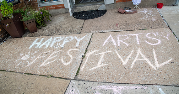Sidewalk chalk that says "Happy Arts Festival"