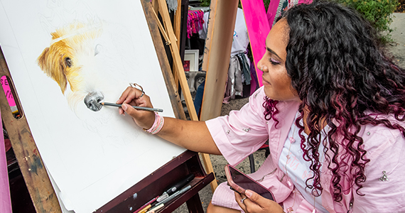 A woman painting a dog portrait.